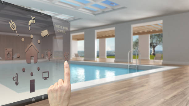 Smart home control concept, hand controlling digital interface from mobile app. Blurred background showing interior swimming pool, architecture interior design stock photo