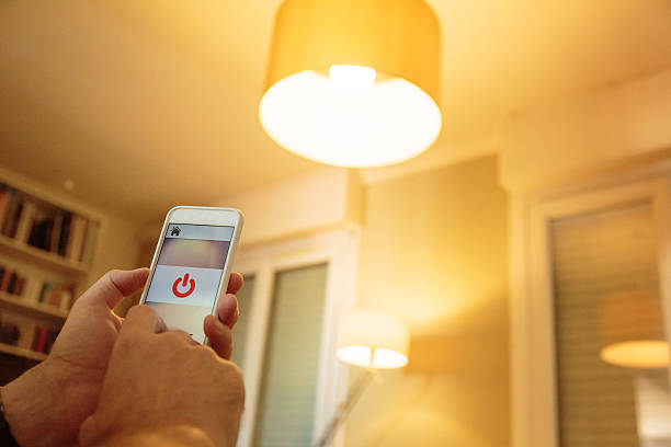 Smart home: man controlling lights with app on his phone stock photo