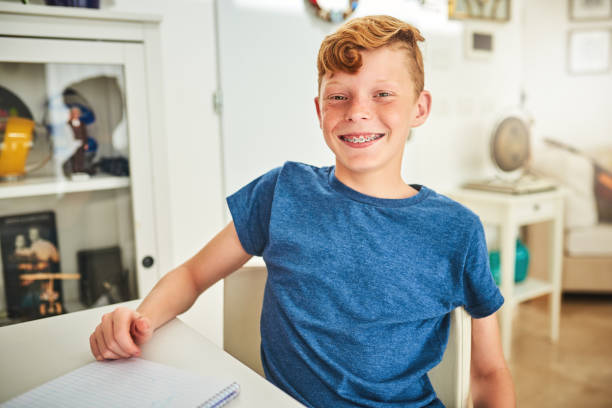 Smart is the new cool Portrait of a handsome young boy doing his homework at home dental braces stock pictures, royalty-free photos & images
