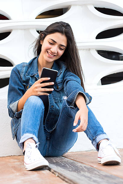 Smart phone Hispanic teenage girl looking at her smart phone pretty mexican girls stock pictures, royalty-free photos & images