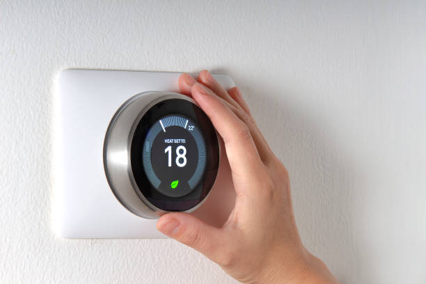 Smart Thermostat with a hand saving energy Smart Thermostat with a hand saving energy thermostat stock pictures, royalty-free photos & images