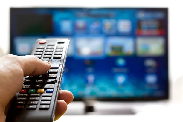 Smart tv and hand pressing remote control stock photo