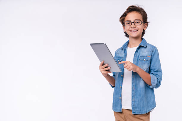 slimme jonge witte jongen die tablet in toevallige uitrusting gebruikt die over witte achtergrond wordt geïsoleerd - jongens stockfoto's en -beelden