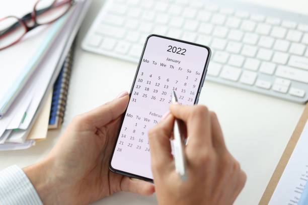 Smartphone on screen with calendar for 2022 pen in female hands stock photo