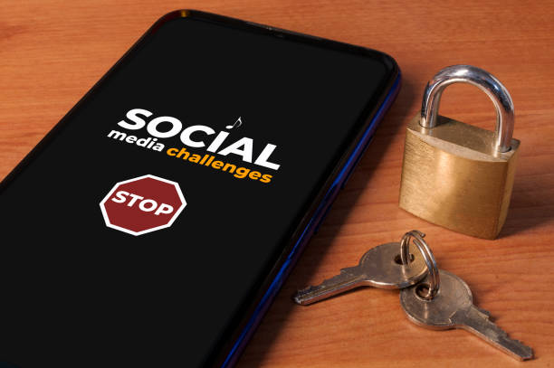 smartphone met het bericht "stop social media challenges" een houten tafel met een slot en sleutels. - tiktok stockfoto's en -beelden