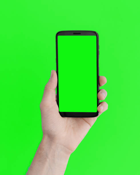 Smartphone with a green screen in left hand on an green background.  smart phone green background stock pictures, royalty-free photos & images