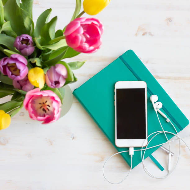 Smartphone with earbuds, journal and tulips stock photo