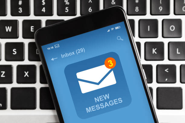 smartphone con nueva notificación de mensaje de correo electrónico en la pantalla acostado en el teclado portátil - email fotografías e imágenes de stock