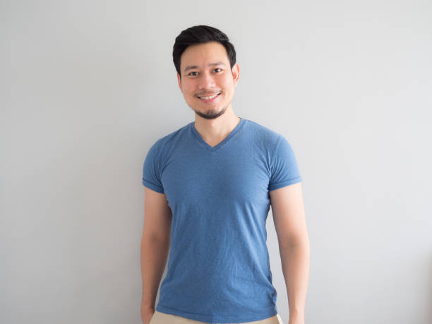 Smile and happy man in blue t-shirt and grey background. stock photo