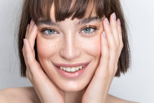 Smile sunshine Close up studio shot of a beautiful girl with short brown hair, freckles and soft make up. bangs hair stock pictures, royalty-free photos & images