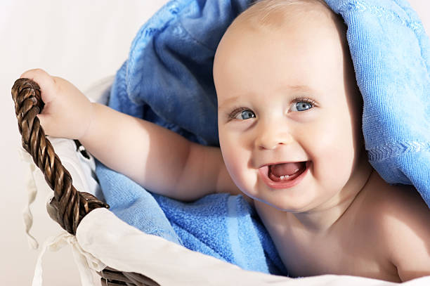Smiley baby boy sitting in basket after bath stock photo