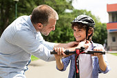 istock Smiling adult man putting safety helmet on his son 1315139874