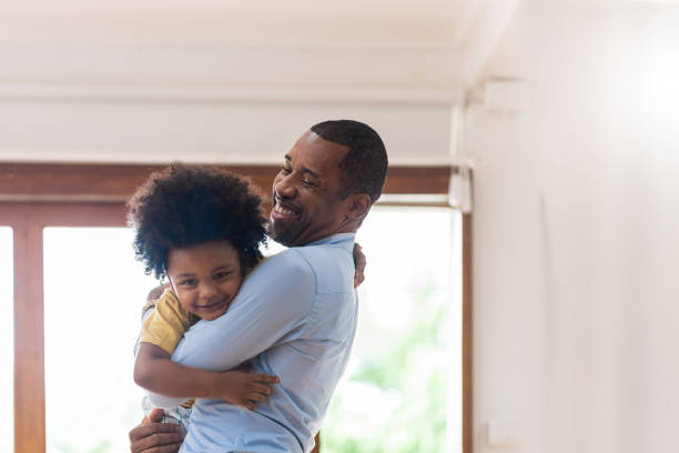 Smiling African American father holding his cute loving little son. stock photo