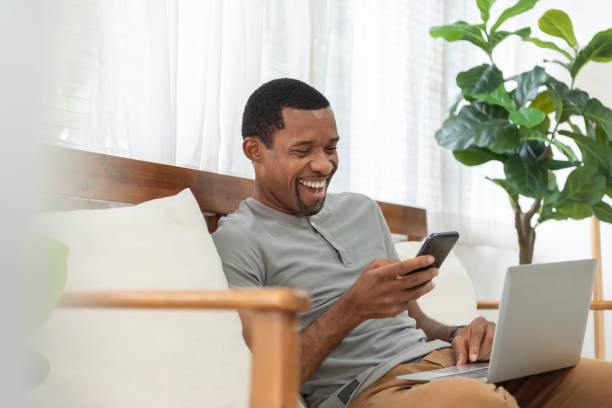 lächelnder afroamerikanischer mann macht online-videoanruf auf dem handy - einzelner mann über 30 stock-fotos und bilder