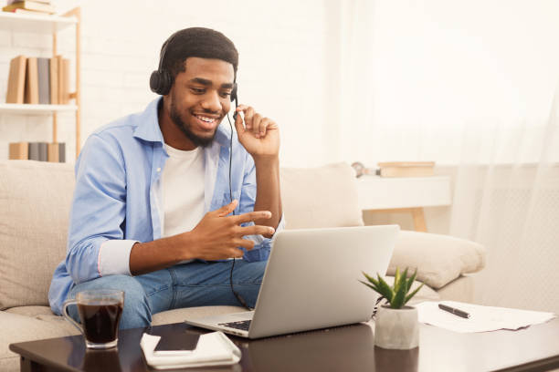 Smiling african-american guy in headphones looking at laptop Smiling african-american guy in headphones studying foreign language online through video conference application, copy space male likeness stock pictures, royalty-free photos & images