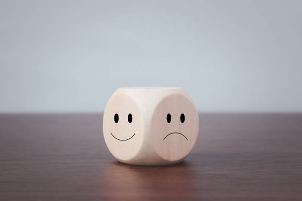Smiling and sad symbols on wooden blocks on a gray background Smiling and sad symbols on wooden blocks on a gray background. emotion stock pictures, royalty-free photos & images