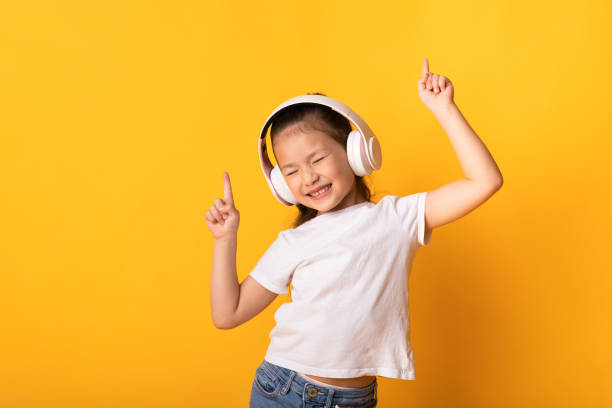 lächelnde asiatische mädchen genießen musik mit kopfhörern - tanzende kinder stock-fotos und bilder