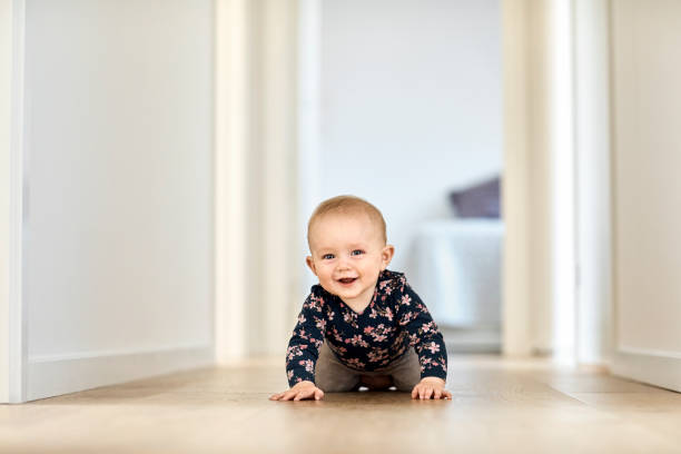 Smiling baby boy crawling in corridor at home Portrait of cute baby boy crawling in corridor. Smiling male toddler is wearing casuals. He is at home. crawling stock pictures, royalty-free photos & images