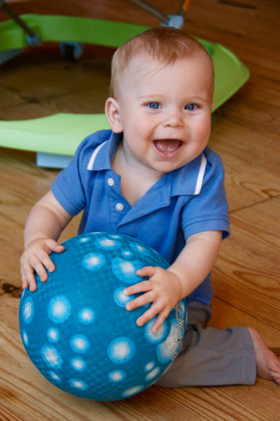 Smiling baby boy holding a ball stock photo