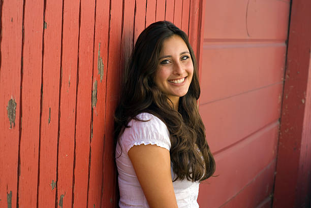 Smiling beauty leaning against red barn wall stock photo