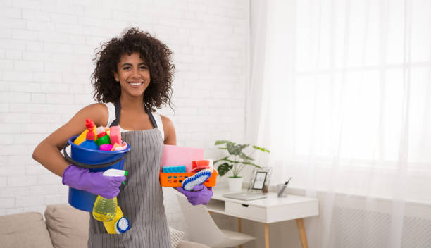 Smiling black woman posing with cleaning supplies Smiling african-american woman posing with cleaning supplies, housewife preparing detergents for housecleaning, copy space maid stock pictures, royalty-free photos & images