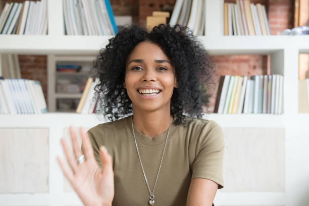 Smiling black woman waving talking on webcam Happy african American millennial woman wave talk on webcam or having skype conversation, smiling positive black female blogger shoot record new blog or vlog, greeting say hello to followers audience vlogging stock pictures, royalty-free photos & images