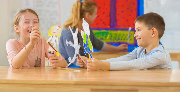 Smiling boy and girl playing with their puppets stock photo