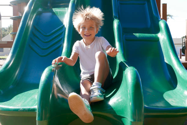 Smiling boy on slide with hair sticking up stock photo