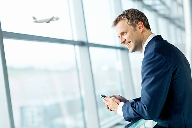 Smiling Businessman Looking Out Airport Window. stock photo