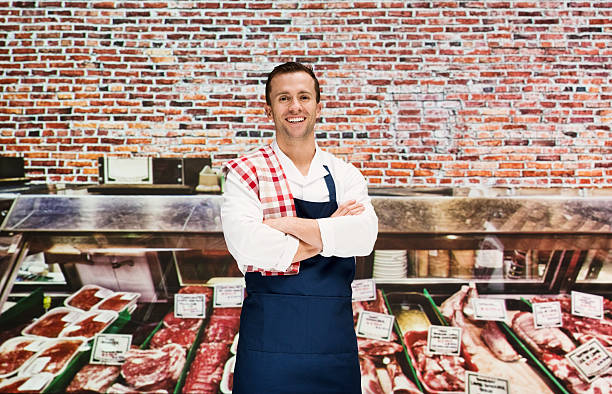 Smiling butcher standing in shop stock photo