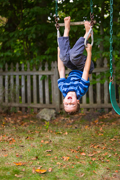 Smiling child upside down on backyard swing set stock photo