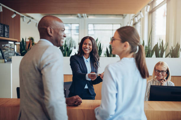 Smiling concierge helping two guests check in to a hotel stock photo