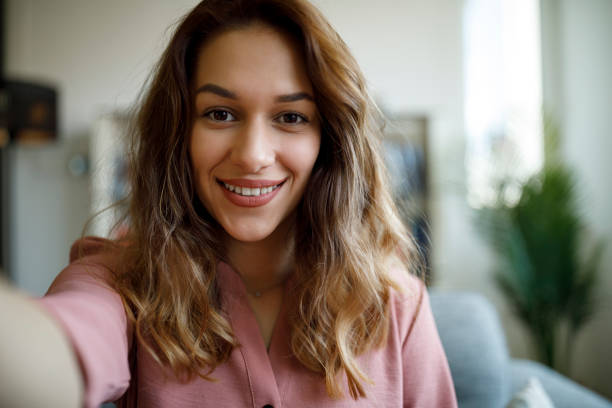 smiling confident young woman having online conference from home office - selfie stok fotoğraflar ve resimler