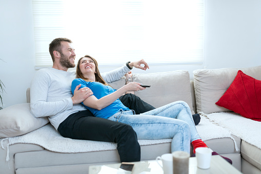 Smiling Couple At Home Watching Tv And Lying On Sofa Stock Smiling Couple At Home Watching Tv And Lying On Sofa Stock