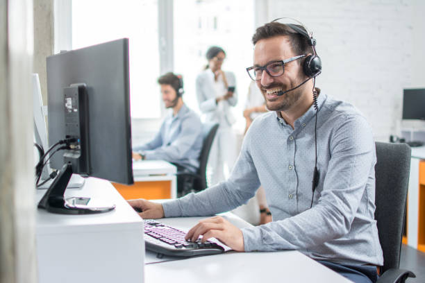 Smiling customer support operator with hands-free headset working in the office. stock photo