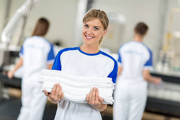 Smiling employed holding clean and ironing textiles Smiling employed holding clean and ironing textiles in chemical cleaners laundromat photos stock pictures, royalty-free photos & images