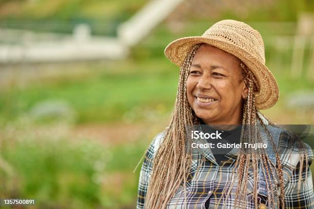 Smiling ethnic farmer in straw hat on plantation