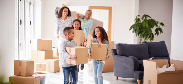lachende familie dragen dozen in nieuw huis op bewegende dag - huis kopen stockfoto's en -beelden