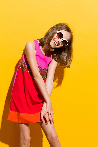 Smiling fashionable girl in sunglasses Smiling fashionable girl in sunglasses posing in mini dress. Three quarter length studio shot on yellow background. girls in very short dresses stock pictures, royalty-free photos & images