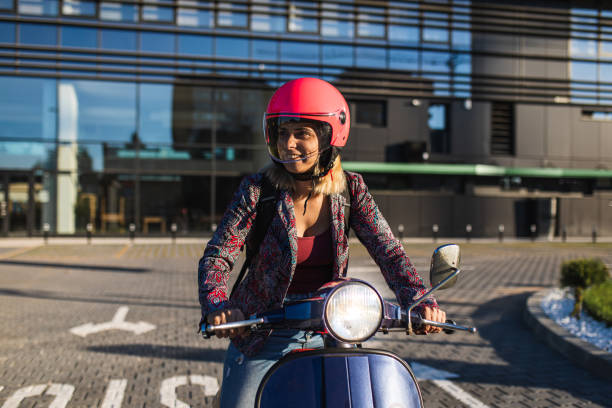Smiling female biker driving scooter stock photo