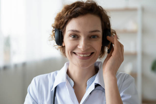 Smiling female doctor wearing headset looking at camera, portrait Smiling female doctor wearing headset looking at camera. Remote online medical chat consultation, telemedicine distance services, virtual physician conference call concept. Head shot close up portrait mental health professional photos stock pictures, royalty-free photos & images