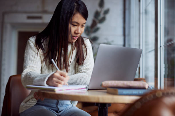 A smiling female student is sitting in a coffee shop and studying. A smiling female student is sitting in a coffee shop and studying. free degree stock pictures, royalty-free photos & images