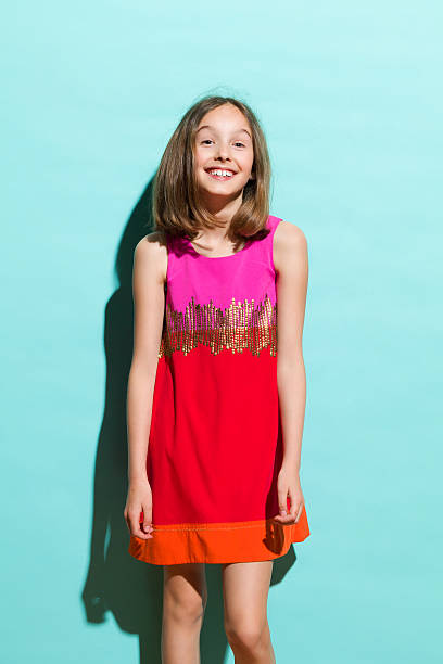 Smiling girl on turquoise background Happy teen girl in red mini dress. Three quarter length studio shot on teal background. girls in very short dresses stock pictures, royalty-free photos & images