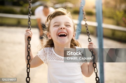 istock Smiling girl playing on the swing 1252210017