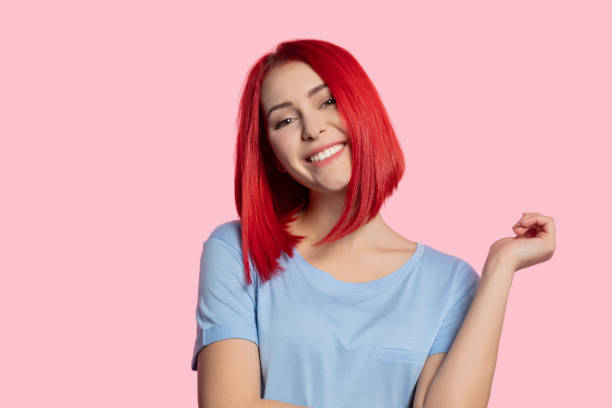 Smiling girl with red hair Woman girl with red hair looking at camera with raised hand on pink background. pink hair stock pictures, royalty-free photos & images