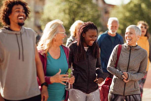 glimlachende groep mensen lopen samen buiten - gemeenschap stockfoto's en -beelden