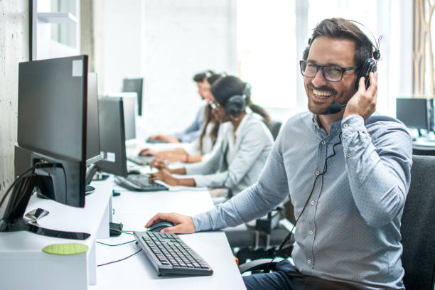 Smiling handsome customer support operator with headset working in call center. stock photo