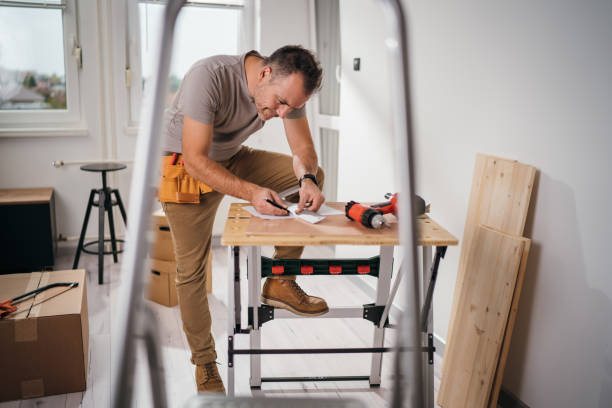 Smiling hard working carpenter underlining part of blueprint using pencil and a ruler stock photo