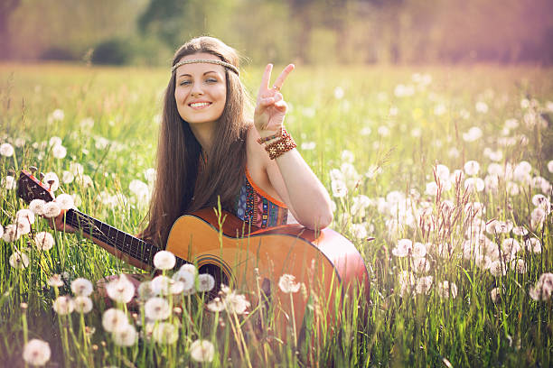 Smiling hippie woman giving peace sign stock photo