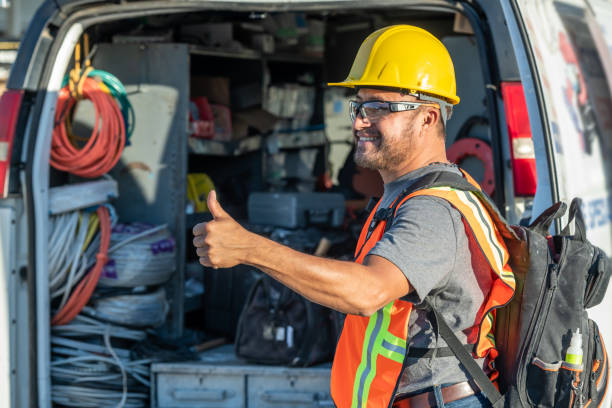 Smiling hispanic construction worker wearing a work helmet looking away with his thumbs up stock photo